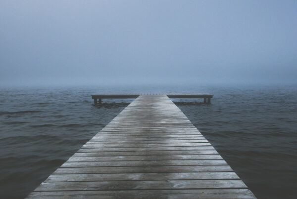 Drewniany pomost nad jeziorem, w oddali mgła