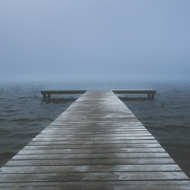 Drewniany pomost nad jeziorem, w oddali mgła